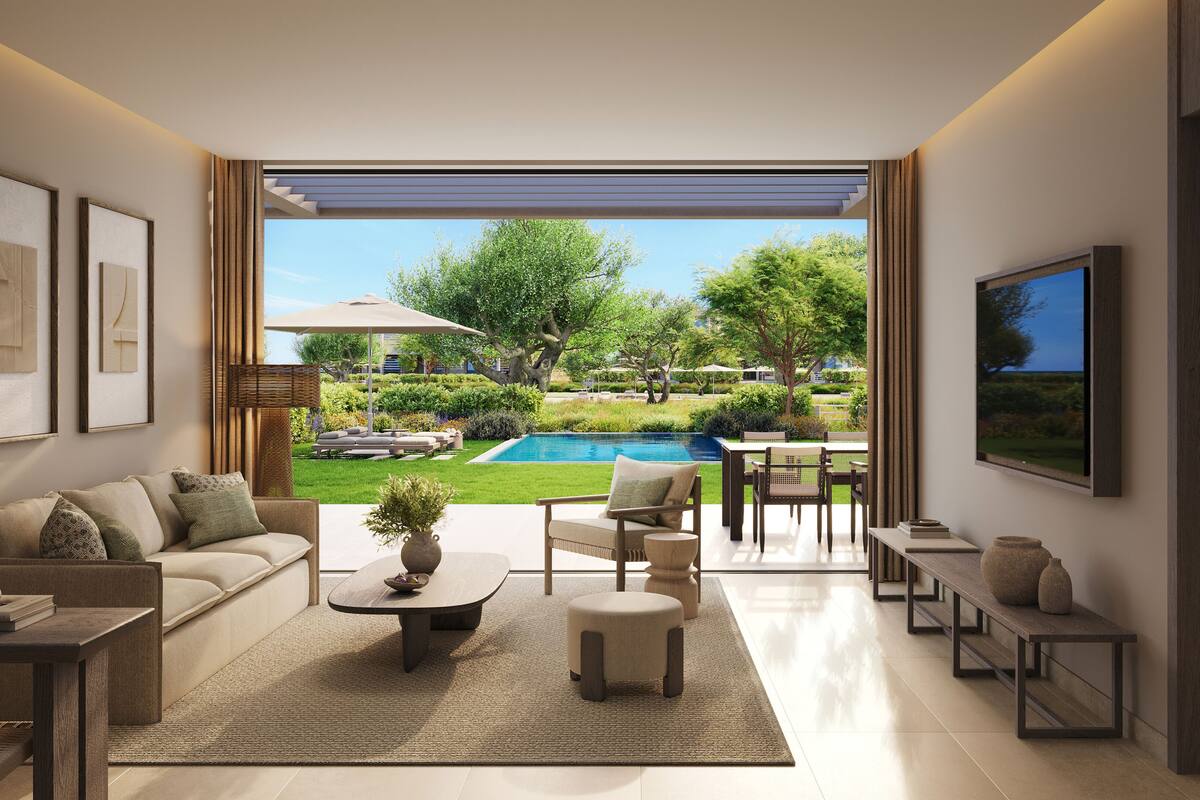 Un moderno salón con vistas a una piscina y jardín, que incluye un sofá, una mesa de centro y un televisor.