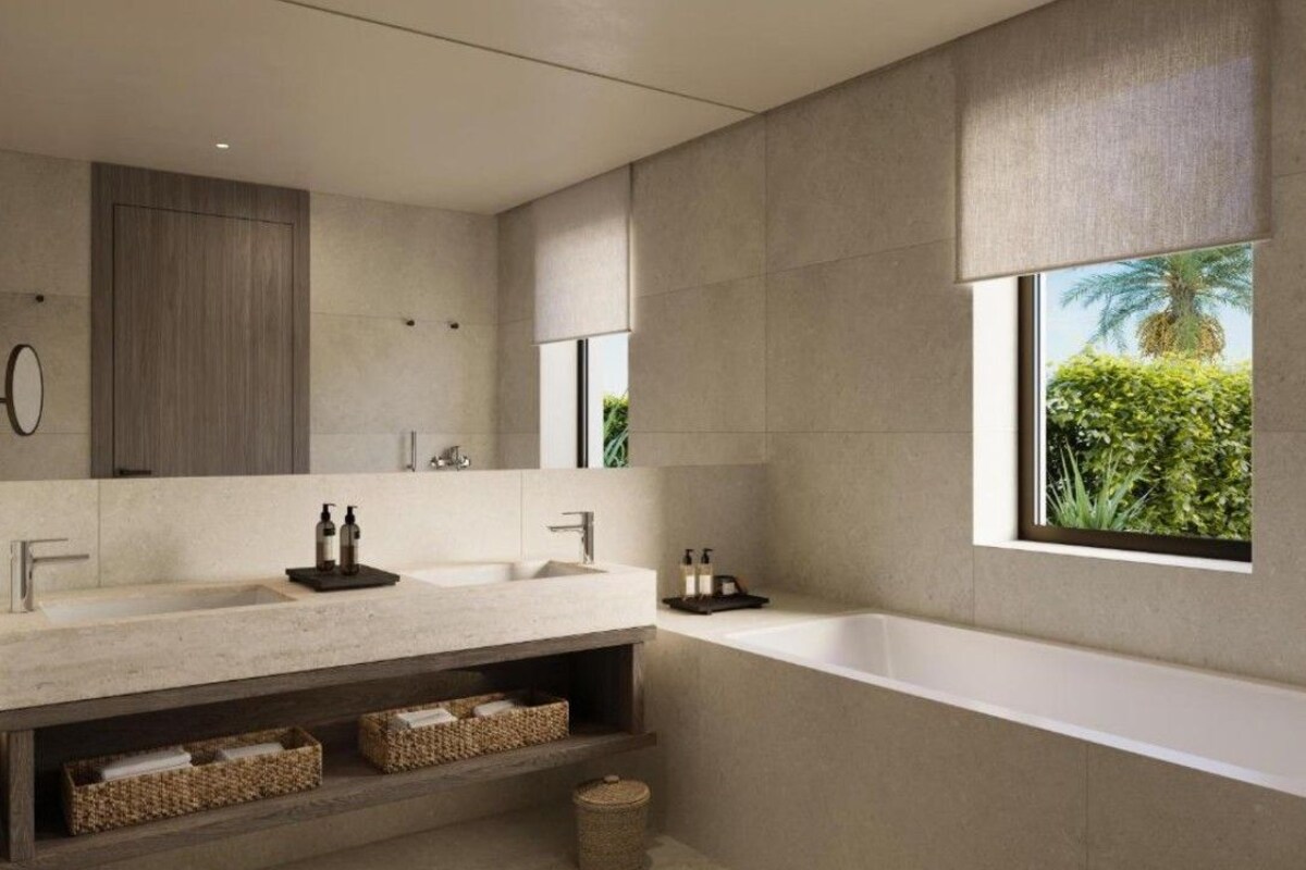 A modern bathroom with a large mirror, two sinks, a bathtub, and a window with a view of greenery.