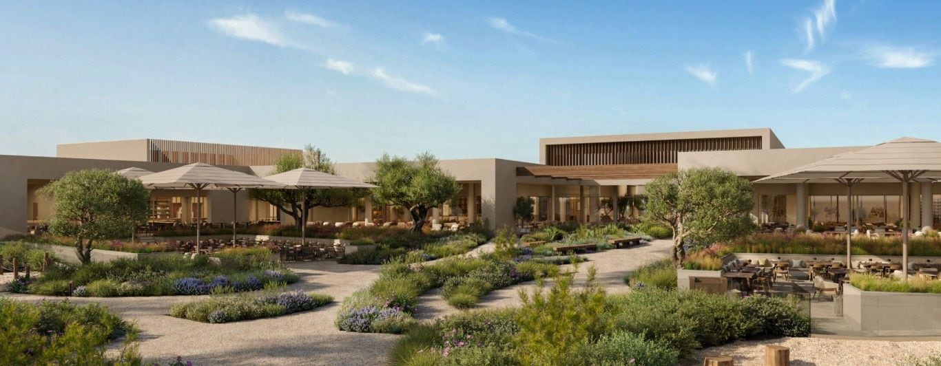 A modern building with outdoor seating areas, surrounded by landscaped gardens and pathways.