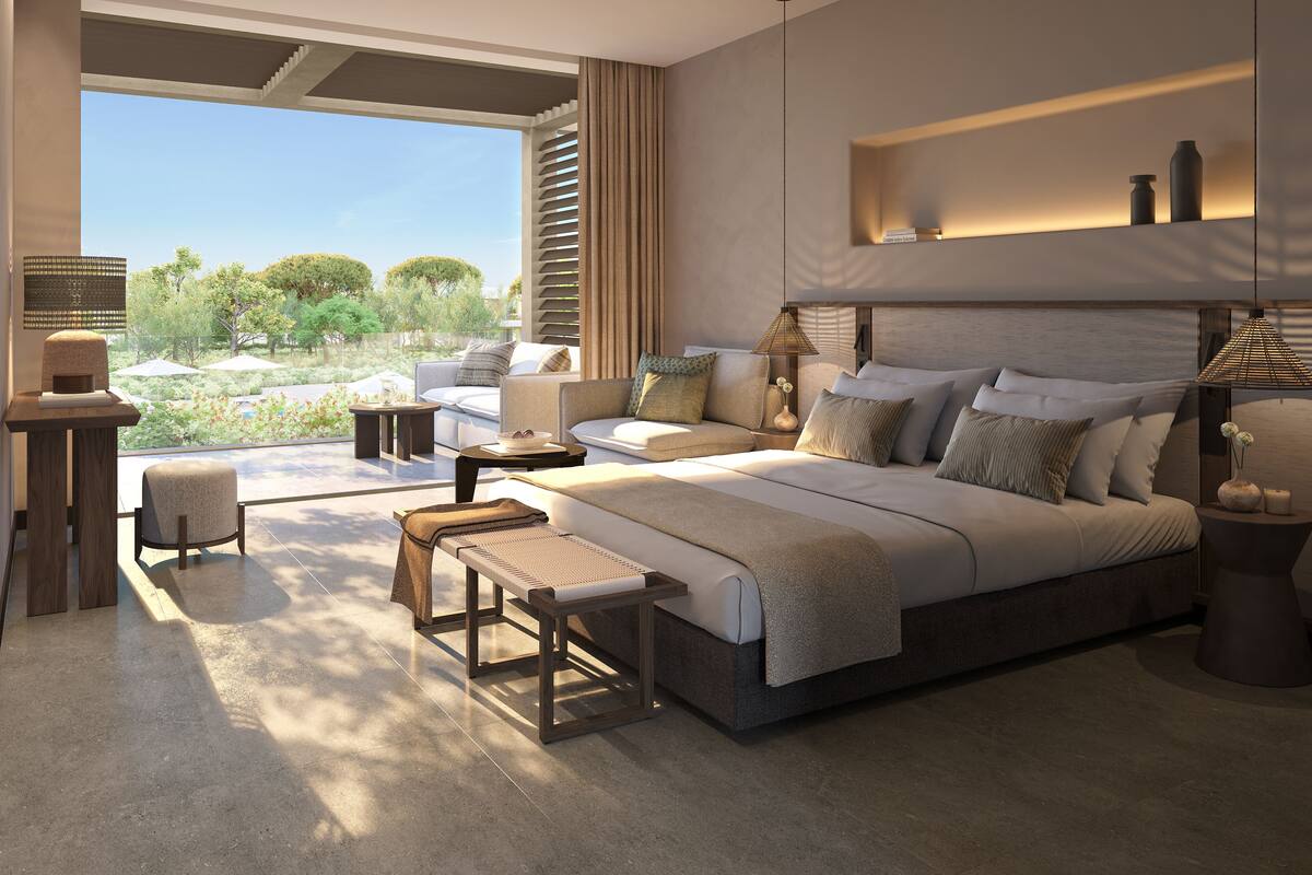 Un dormitorio moderno con una cama grande, un rincón de descanso y vistas al exterior.