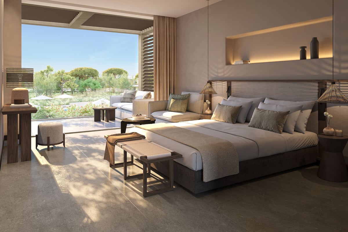 A modern bedroom with a large bed, a seating area, and a view of the outdoors.