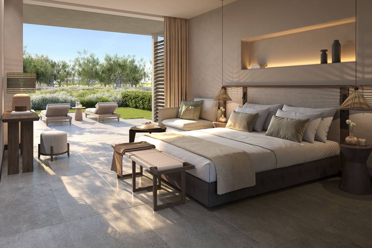 Un dormitorio moderno con una cama grande, un espacio de descanso con sofá y sillones, y vistas a un jardín.