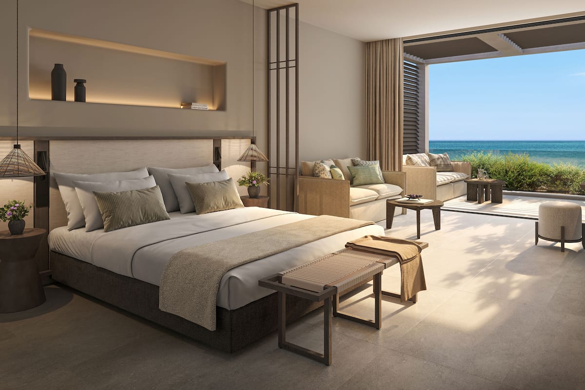 A modern bedroom with a large bed, bedside tables, a nightstand, and a view of the ocean.