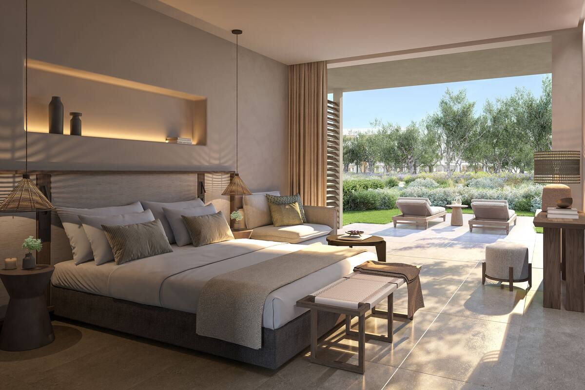 Un dormitorio moderno con una cama grande, mesitas de noche, un sofá y vistas a un jardín.
