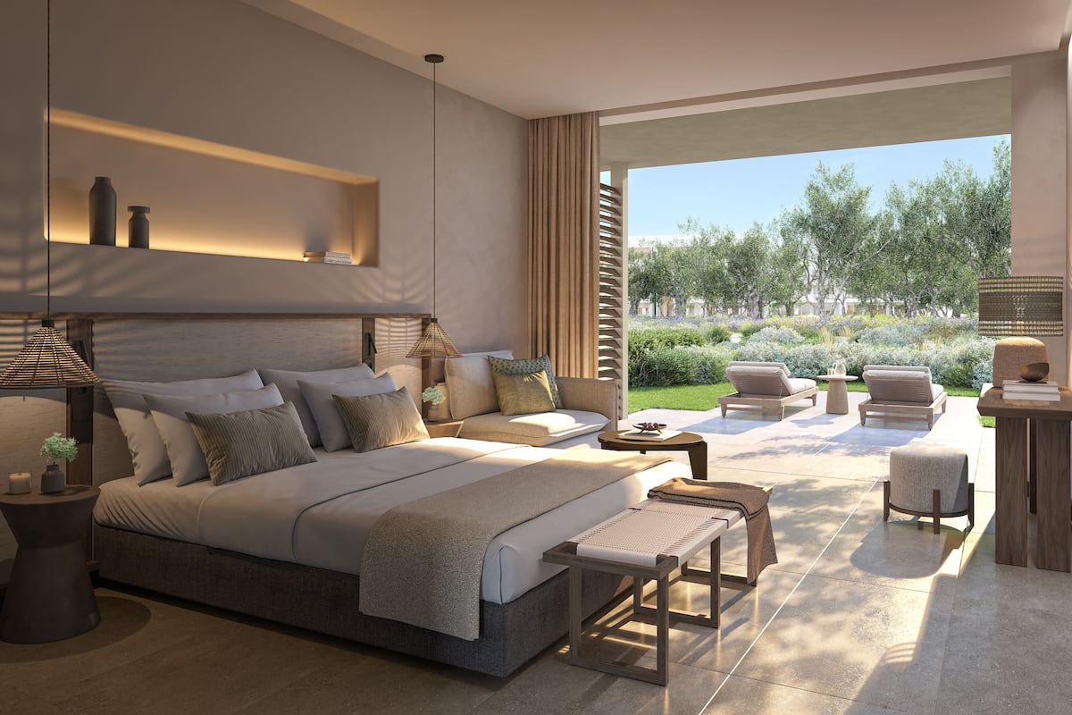 A modern bedroom with a large bed, bedside tables, a sofa, and a view of a garden.