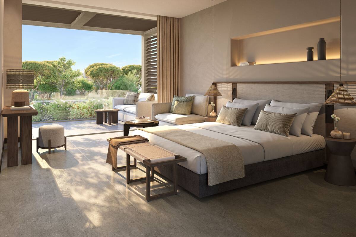 Un dormitorio moderno con una cama grande, zona de estar y vistas a zonas verdes.