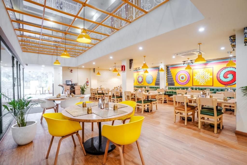 A spacious restaurant with high ceilings, yellow chairs, and a variety of seating arrangements.