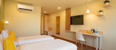 A hotel room with two beds, a desk, a chair, a TV, and a wall-mounted air conditioner.
