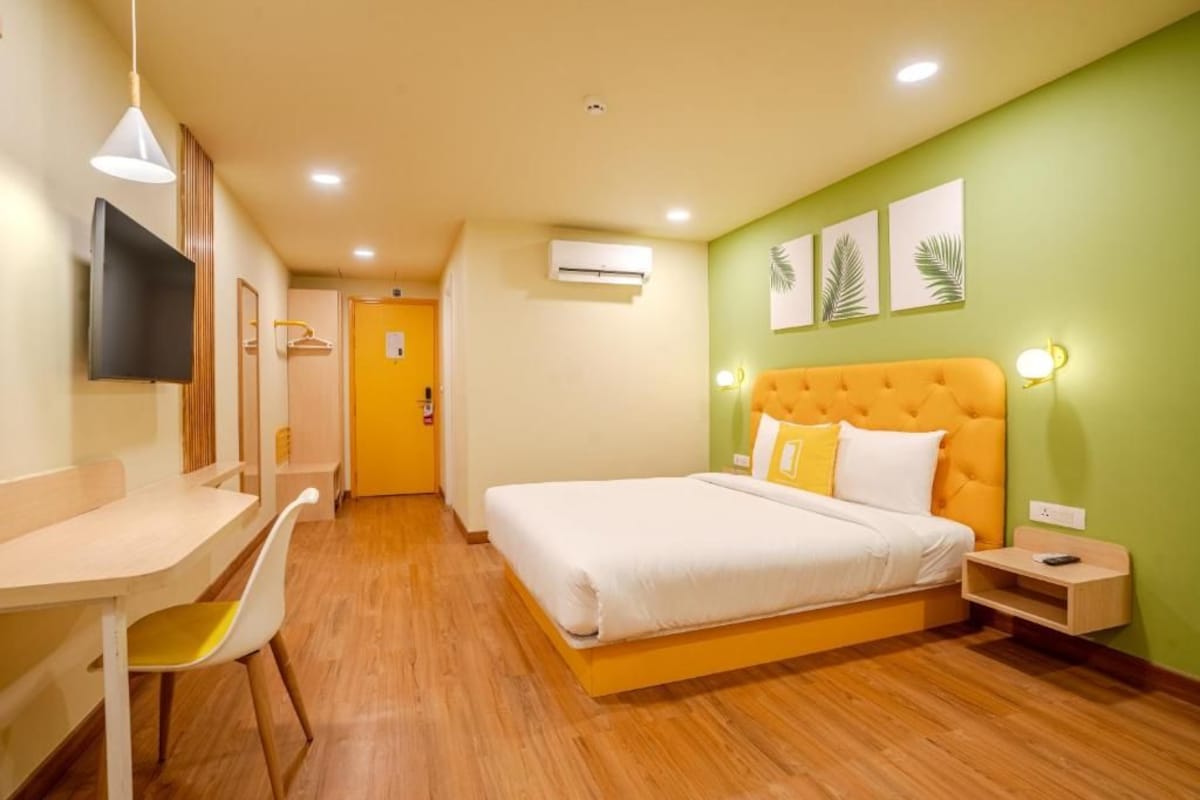 Habitación de hotel con cama, escritorio, silla, equipo de aire acondicionado y televisor.