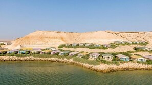 Una località balneare con ville lungo una costa rocciosa, cieli sereni e un'imponente scogliera sullo sfondo.