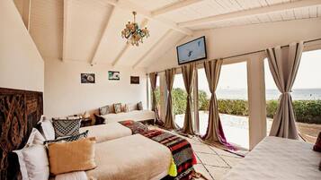 A bedroom with a large bed, a television, and a view of the sea.