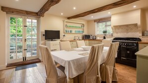 Un comedor con mesa, sillas, televisor y cocina equipada con estufa y microondas.