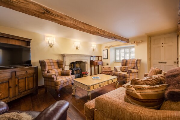 A cozy living room with a fireplace, plaid furniture, and a television.