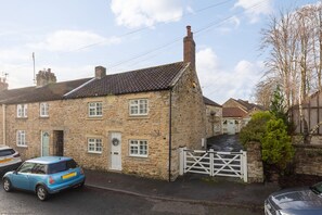 A stone building with a traditional design, a gated driveway, and a parked car.