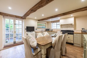 A kitchen with a wooden table and chairs, a stove, a microwave, and a TV.