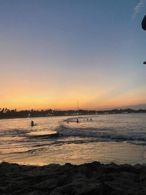 A beach scene with waves and a distant city skyline. - The Calm Of8 Arugambay (Arugam Bay)
