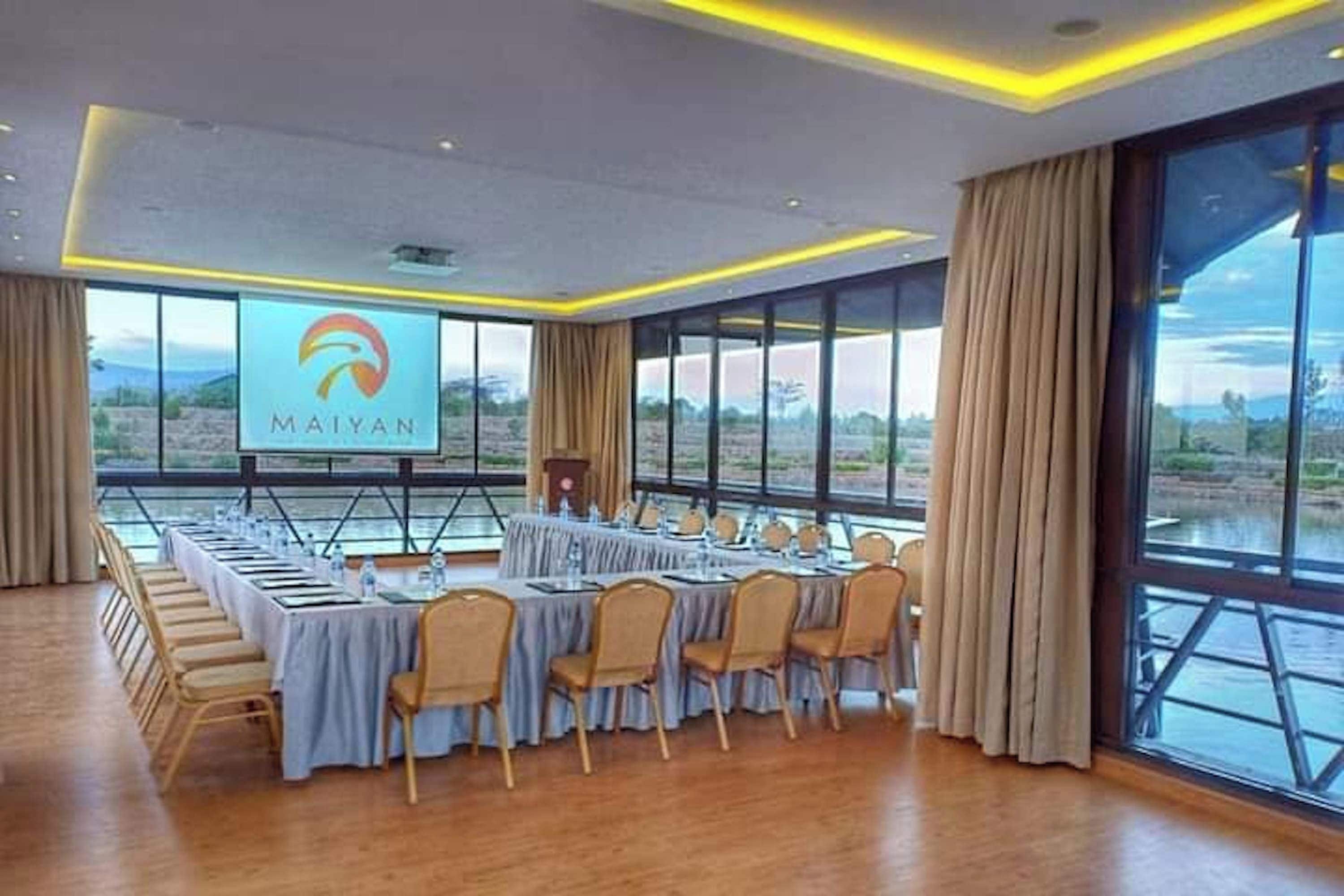 A conference room with a long table, chairs, a podium, and a large screen displaying the 'MAIYAN' logo.