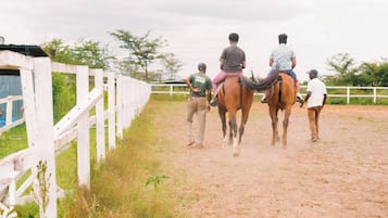A horse riding activity with participants and horses in an outdoor area with a white fence.