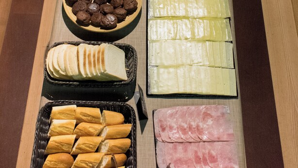 Una mesa de buffet con diferentes alimentos, incluyendo pan, pasteles y embutidos.