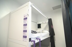 A bunk bed with a headboard, a small shelf, and a wall-mounted light fixture. - Kabul Party Hostel (Barcelona)