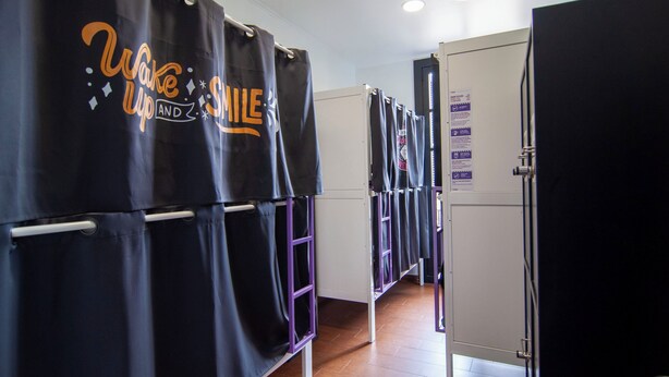 A hotel bathroom with multiple shower stalls, each with a curtain displaying the text 'Wake Up and Smile.' - Kabul Party Hostel (Barcelona)