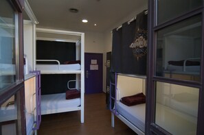 A dormitory room with bunk beds, a door, and a window. - Kabul Party Hostel (Barcelona)