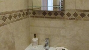 A bathroom with a white sink, a mirror, and a toilet. - Woodman Inn (Bedale)