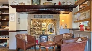 A cozy room with a fireplace, leather armchairs, and a stone wall. - Woodman Inn (Bedale)