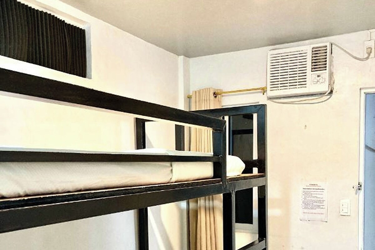 A bunk bed room with a ceiling fan, a door, and a small table with a chair.