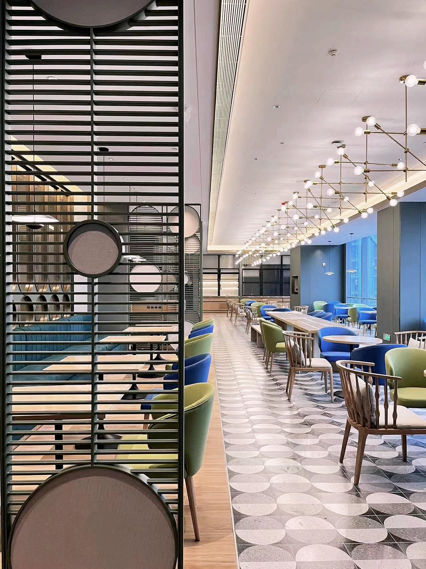 A modern restaurant interior with a long counter, multiple seating areas, and a patterned floor.