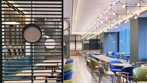 Un restaurante moderno con una barra larga, varias zonas de estar y un suelo estampado.
