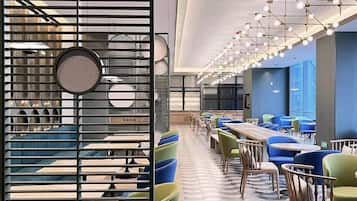 A modern restaurant interior with a long counter, multiple seating areas, and a patterned floor.
