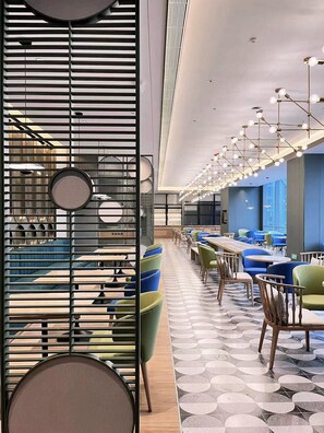 Un restaurante moderno con una barra larga, varias zonas de estar y un suelo estampado.