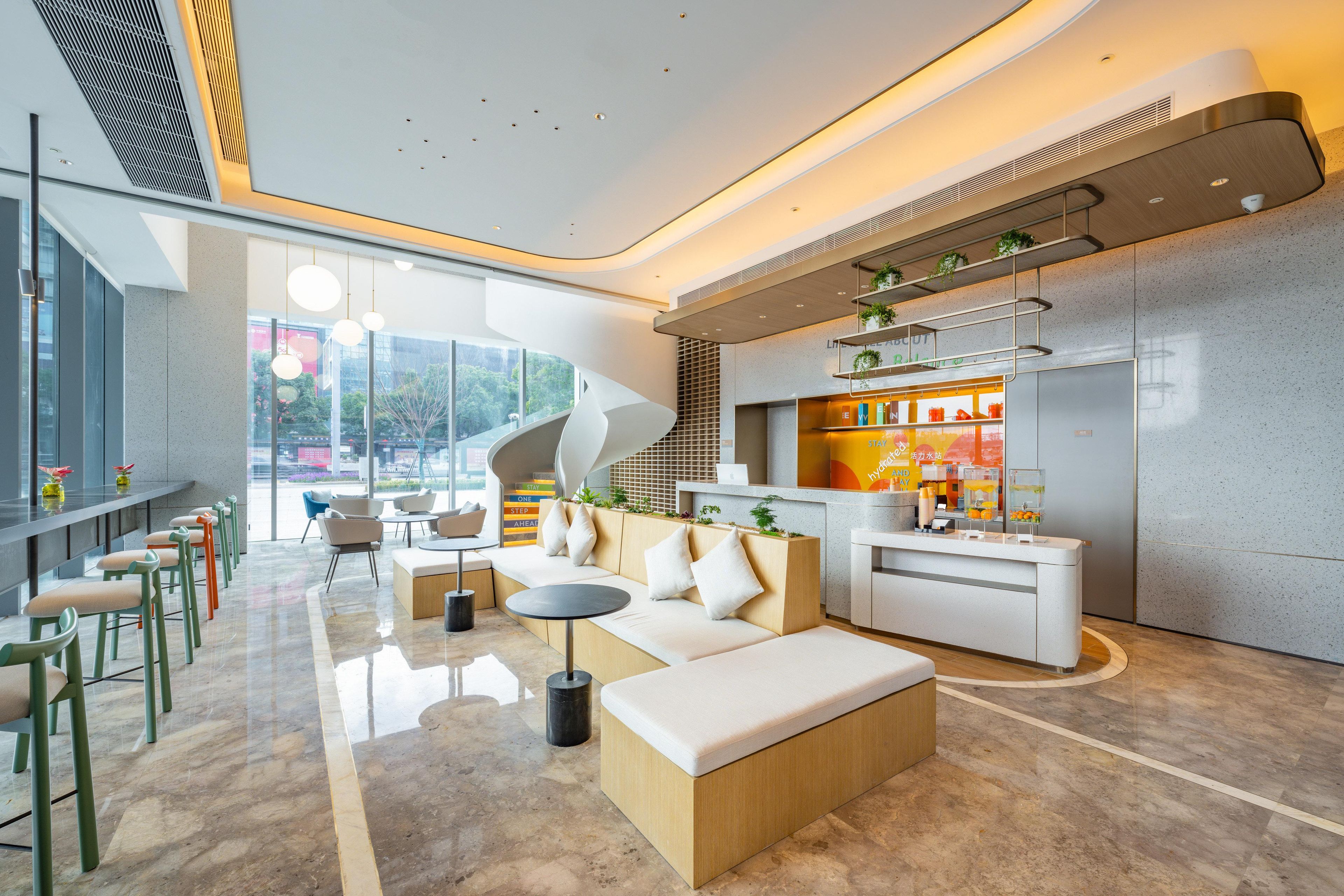 A modern lobby with a seating area, a reception desk, and a kitchen counter.