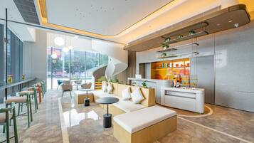A modern lobby with a seating area, a reception desk, and a kitchen counter.