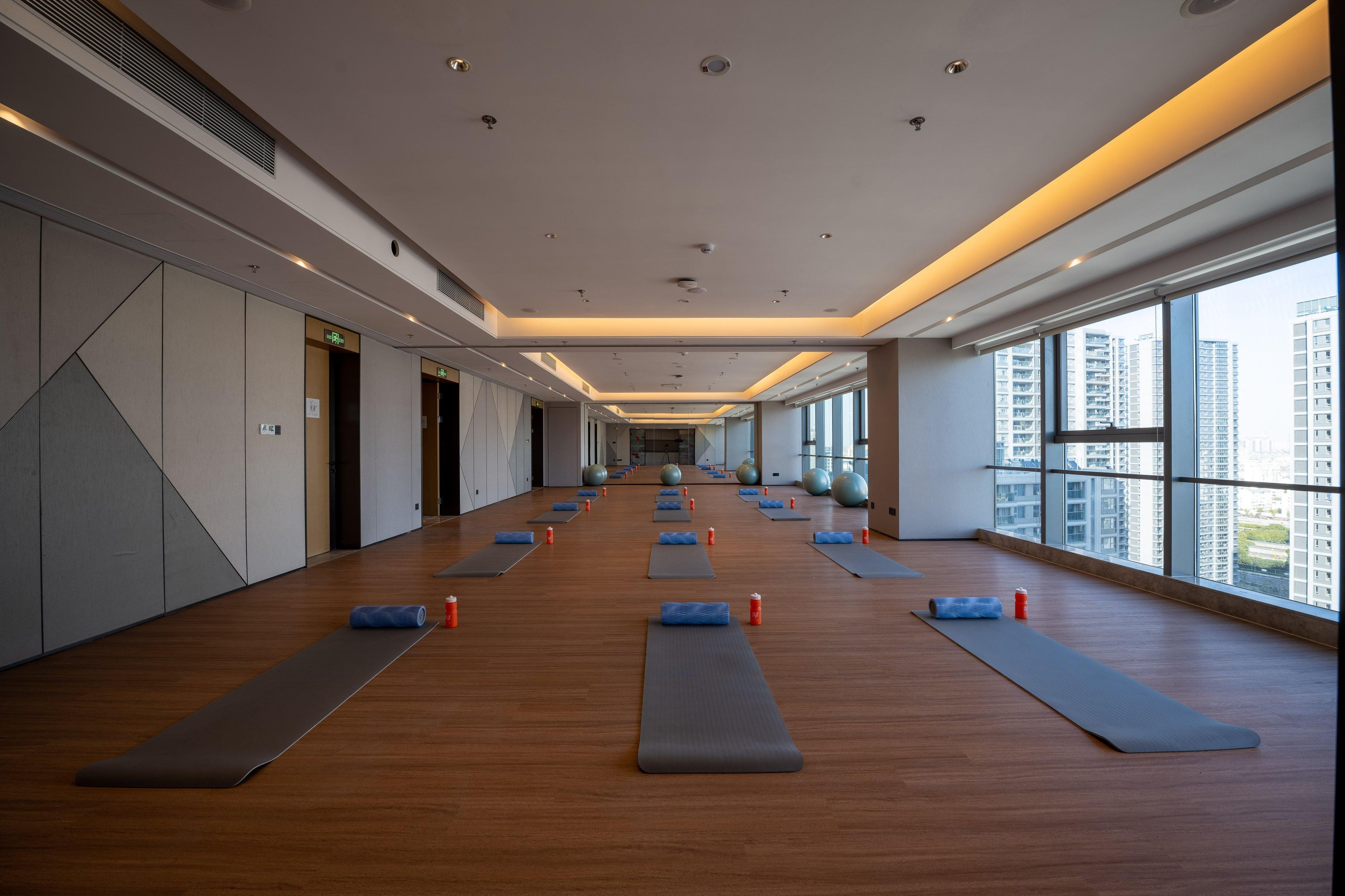 Un gimnasio amplio con colchonetas de ejercicio, pelotas de yoga y piso de madera.
