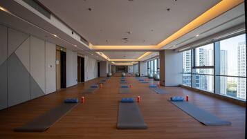 Un gimnasio amplio con colchonetas de ejercicio, pelotas de yoga y piso de madera.