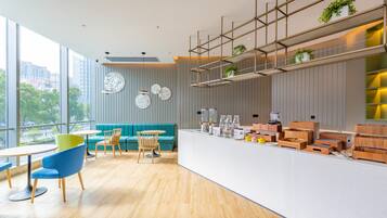 Un interior moderno con suelo de madera, un sofá azul verdoso, sillas azules y una encimera blanca con plantas y cajas de almacenaje.