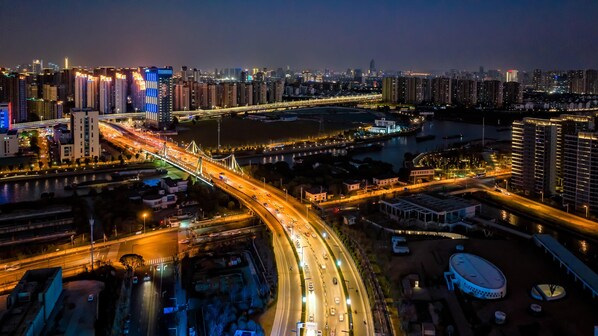 A nighttime cityscape with a prominent bridge, high-rise buildings, and a river. - Even Suzhou Grand Canal (Suzhou)