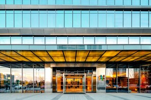 A modern hotel entrance with glass doors, a sign reading 'Well-Come,' and a visible 'Even Hotels' sign. - Even Suzhou Grand Canal (Suzhou)