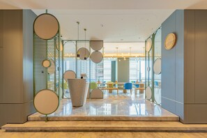 A modern interior with a reception desk, seating area, and large windows. - Even Suzhou Grand Canal (Suzhou)