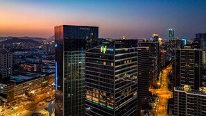 A high-rise hotel with multiple floors, a prominent logo on the top, and a cityscape in the background. - Even Suzhou Grand Canal (Suzhou)