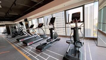 Un gimnasio con cintas de correr, elípticas y un espejo grande.