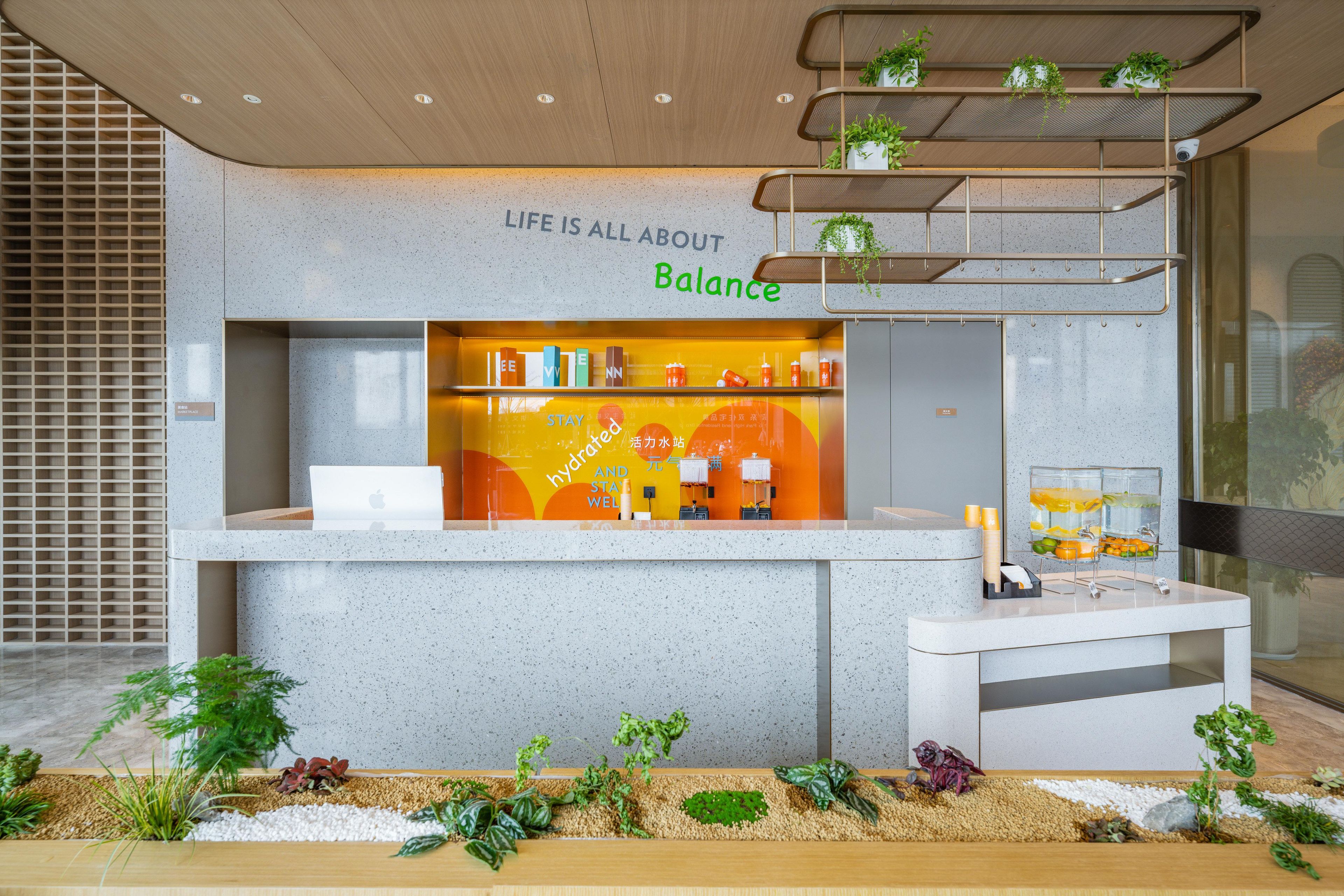 Un mostrador de recepción con un cartel que dice 'Life is all about Balance', una computadora portátil y una estación de agua.