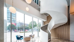 Un interior moderno con una escalera en espiral, ventanas amplias y mobiliario contemporáneo.