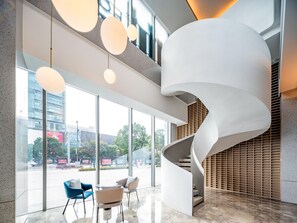 Un interior moderno con una escalera en espiral, ventanas amplias y mobiliario contemporáneo.