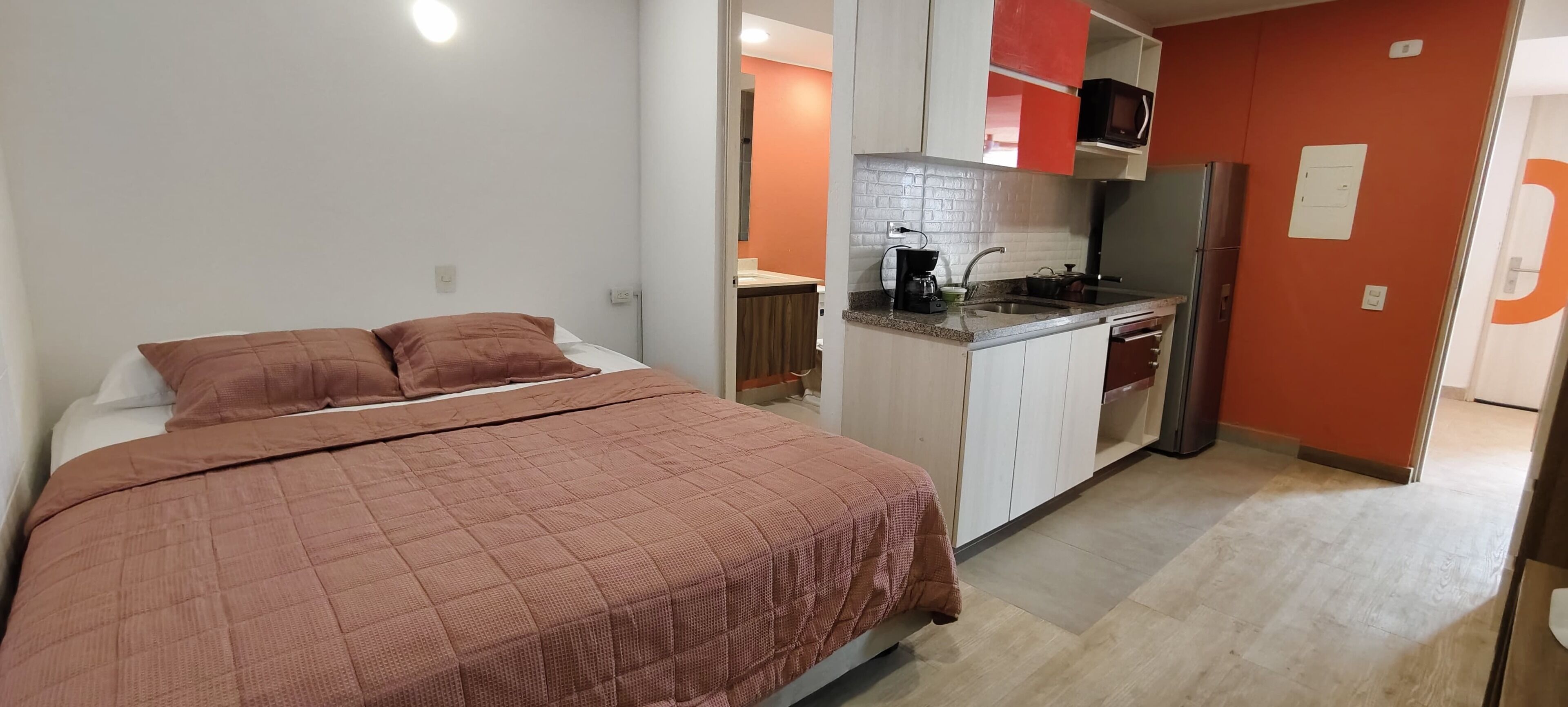 A bedroom with a bed and a kitchenette.