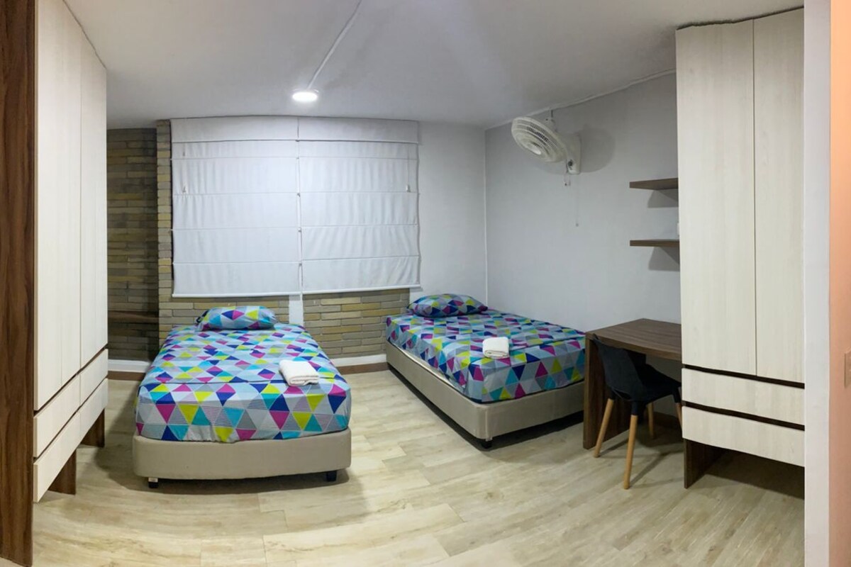 Un dormitorio con dos camas, un escritorio y un armario.