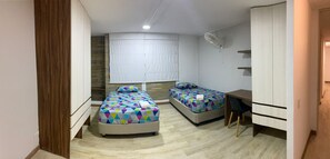 Ein Schlafzimmer mit zwei Betten, einem Schreibtisch und einem Kleiderschrank.
