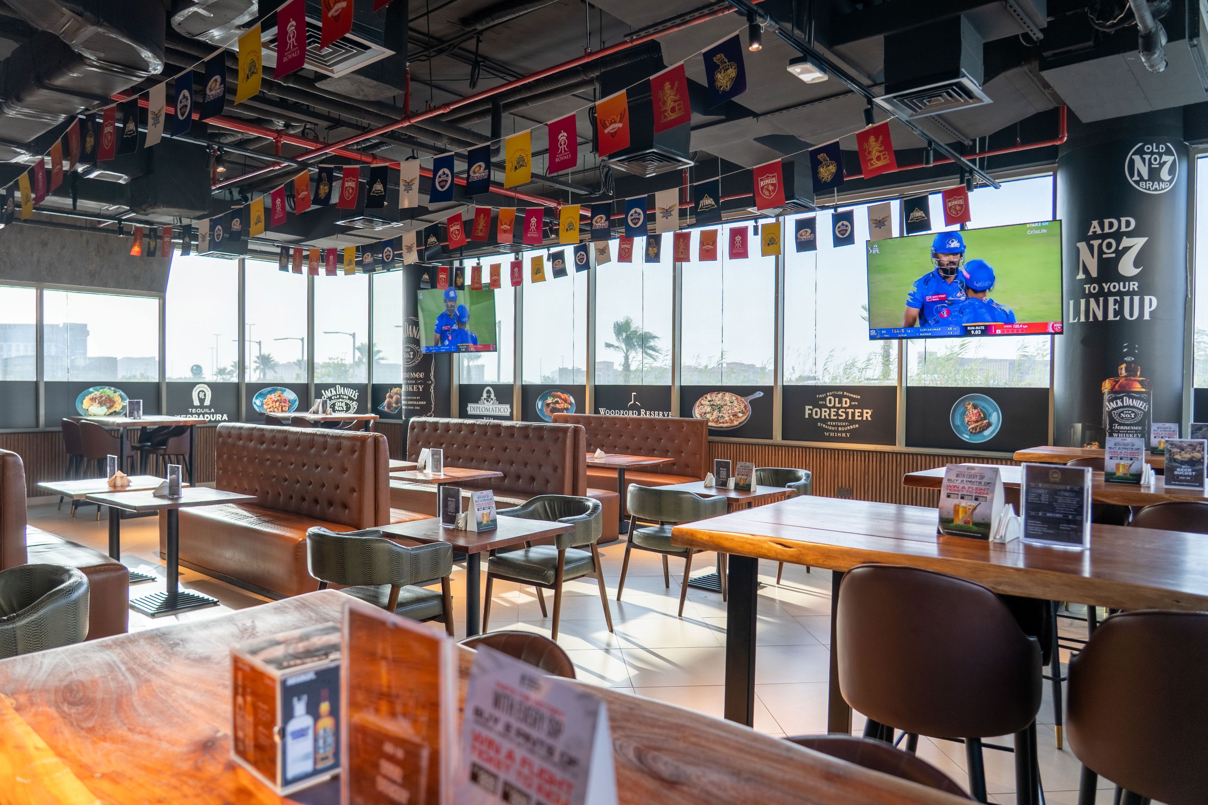 A restaurant interior with booths, tables, and a large TV screen.